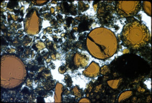 Foto al microscopio che mostra sfere e frammenti di vetro vulcanico (in arancione). La dimensione della sfera più grande ha un diametro pari a 0.2 millimetri - Credit: NASA